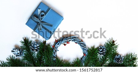 Christmas composition. Wreaths, red berries, fir branches, blue gift box and pine cones on pastel gray background. Christmas, winter, new year concept. Flat lay, top view, copy space.
