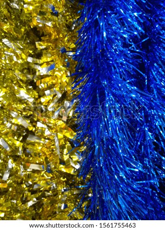 Shiny vertical background of blue and golden Classic Tinsel Garland. Traditional Christmas decorations. Xmas collection. Happy New Year. Winter accessories for holiday decor. Bright colors combination