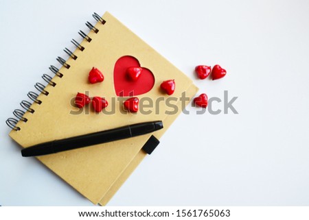 on a notebook with red hearts is a black pen