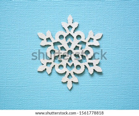 Sparkling white snowflake on textured blue background. Flat lay composition. Winter holidays concept.