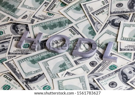 The words HODL laid with aluminium letters on dollar banknotes - with selective focus blur