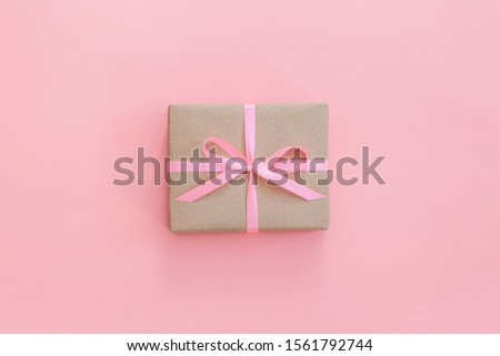 Female hands holding present box or gift box package in craft paper over white background. Top view, flat lay