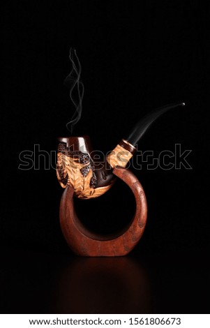 Tobacco pipe with smoke isolated on black background.