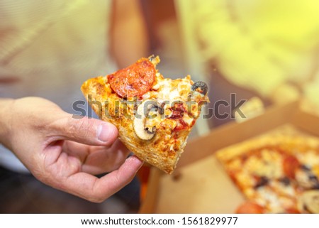 eating vegetarian pizza with tomatoes and olives. hands hold a slice of pizza.