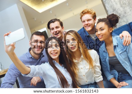 Young men and women having fun indoors taking selfie photos saving moment together for memories smiling joyful