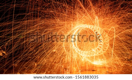 Swing fire Swirl steel wool light photography over the stone with reflex in the water long exposure speed motion style.