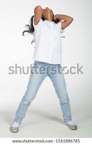 Arab Saudi cute girl wearing jeans and white shirt, wearing headphones, dancing and jumping against white isolated background.