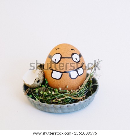 A depiction of a funny face with glasses on an egg in a cute small plate on a white background