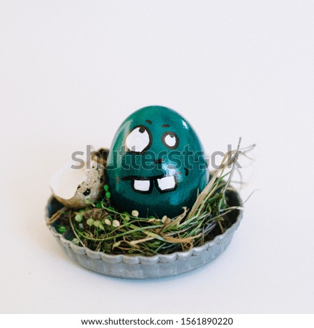 A depiction of an unsure face on a turquoise colored egg in a cute small plate on a white background