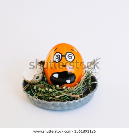 A depiction of a funny terrified face on an orange egg in a cute small plate on a white background