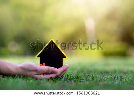 Hand holding mini house on the grass
