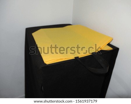 Yellow bag lying on top of the Black table, Box Type Non woven Bag, Eco Bag Stand on Black Table