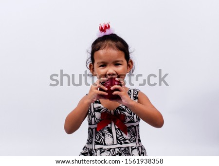Cute asian baby girl with two hand holding apple fruits to eating Isolated on white backgrounds studio lighting
