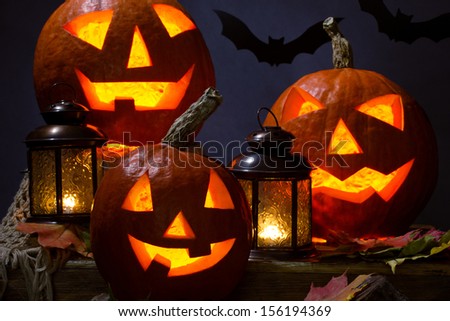 halloween pumpkins and bat with lanterns and maple leafs on dark background