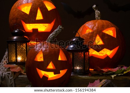 halloween pumpkins with lanterns on wooden table  on dark background with bats