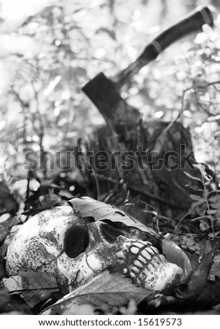 Halloween scary scene - buried skull with killer's hatchet in background