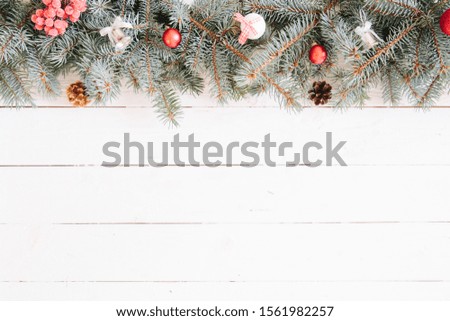 Blurred Christmas background, with fir branches, fairy lights and christmas decorations on white wooden plank