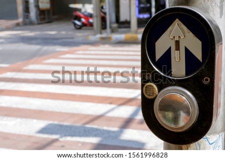 Pedestrian crossing button next to zebra crossing for press and wait signal across to opposite the road.