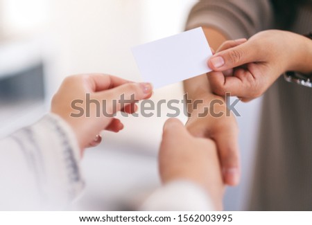 Two people shaking hands and exchanging empty business card 