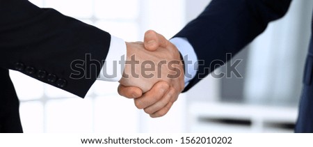 Business people shaking hands after contract signing in modern office. Unknown businessman, male entrepreneur with colleagues at meeting or negotiation. Teamwork, partnership and handshake concept