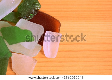 Sea glass scattered on a wooden surface closeup. Top view. Retro style vacation background