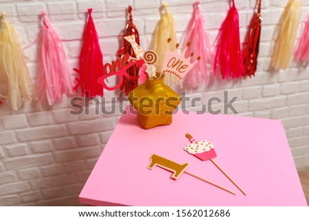 Ideas for decorating pink style first year birthday party for little girl. Paper garlands on a white brick wall and photo booth props. Stylish props One year photo shoot