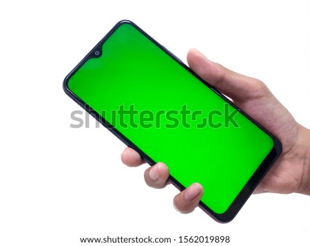 Male hand holding black cellphone with green screen, close up on a white background.