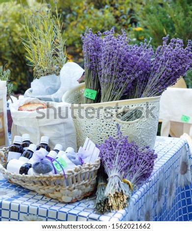  Fresh purple lavender with flacons of essential oil for aromatherapy, alternate medicine and perfumery at market stall. Sale of natural lavender oil in fair outdoor.