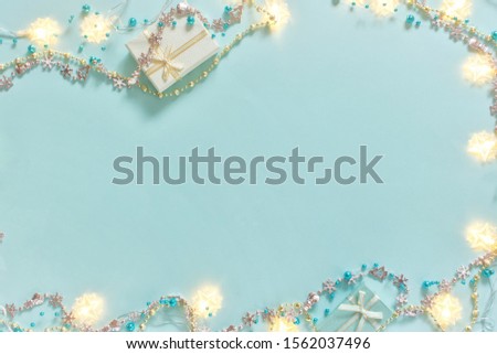 Christmas flatlay. Christmas gifts, shiny, glossy beads, yellow garland decorations on turquoise background. Concept for celebration, carnival, party, festive sales. Flat lay, top view, copy space.