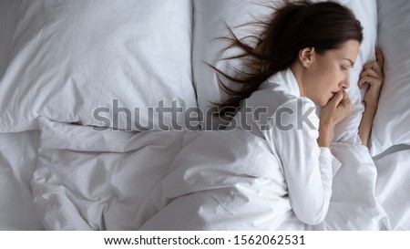 Awoken lonely scared young woman insomniac lying in bed alone suffer from insomnia or disturbing nightmare dream feel depressed anxious worried of problem afraid can not sleep concept, above top view Royalty-Free Stock Photo #1562062531