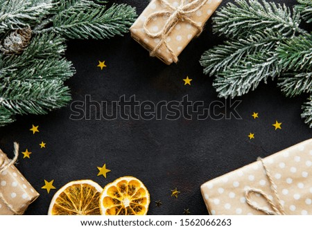 Christmas tree branch with gift box and decorations on black concrete  background with copy space