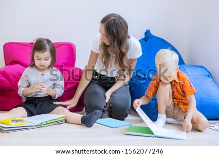 Female teacher teaching her students to read a book while sitting in the classroom
