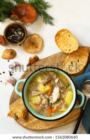 Homemade hot vegetable soup with mushrooms and bulgur on a white countertop. Top view flat lay background.
