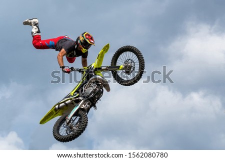 A man jumping with a motocross bike for fun. Blue cloudy sky background.