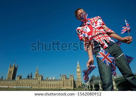 Frustrated man tangled in colorful Union Jack bunting standing in front of the city skyline at Westminster, London, UK