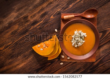 Warm autumn cream pumpkin soup on a wooden table. Diet food. Top view