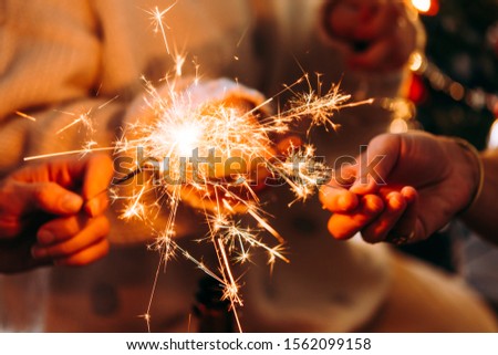 Friends celebrating Christmas or New Year eve party with Bengal lights and champagne. Royalty-Free Stock Photo #1562099158