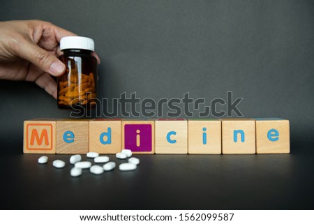 Hand holding medicine bottle and medicine words is building up with text wooden block. Colourful alphabet wood cube for learning and playing in school. Health care conceptual for hospital and clinic