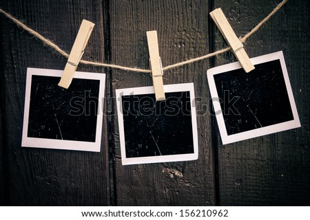 Photo paper attach to rope with clothes pins on wooden background 