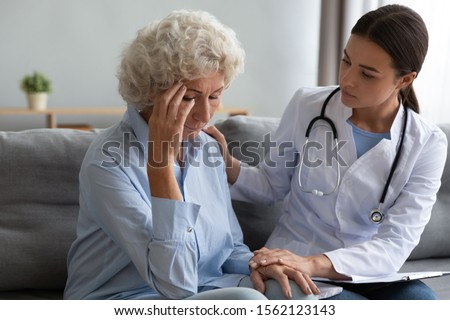 Young caring female caregiver nurse doctor supporting helping comforting sad depressed senior grandmother patient having disease health problem give empathy consoling concept at medical consultation Royalty-Free Stock Photo #1562123143