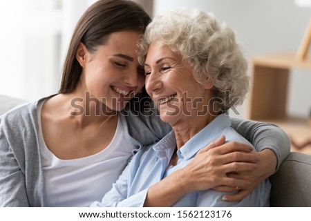Positive smiling old grandma mother and young adult granddaughter daughter bonding at home, happy two generation women family laughing hugging having fun enjoying time together at reunion meeting Royalty-Free Stock Photo #1562123176