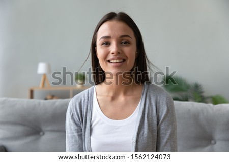 Smiling attractive young lady blogger talking to camera recording blog vlog, happy pretty woman looking at webcam making video conference call online chat distant job interview at home, web cam view Royalty-Free Stock Photo #1562124073