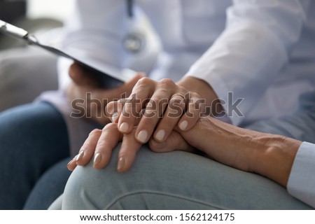 Young woman doctor nurse wear white medical uniform holding hand of senior old female grandmother patient having disease health problem give support help empathy and comfort concept, close up view Royalty-Free Stock Photo #1562124175
