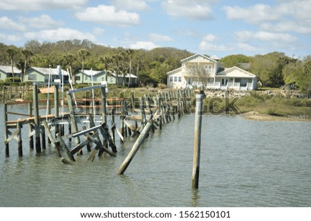 wooden poles on water leading to a building