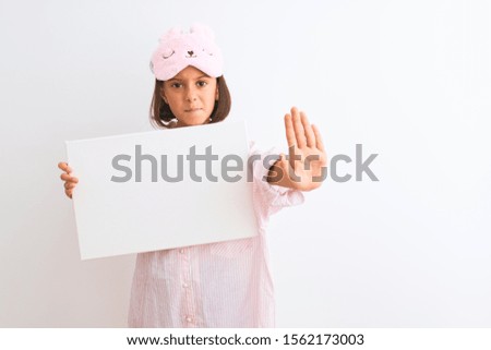 Child girl wearing sleep mask and pajama holding banner over isolated white background with open hand doing stop sign with serious and confident expression, defense gesture