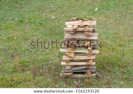 A tower of firewood is drying on a lawn. Ecological fuel for the furnace. Fuel for stove heating. Country life. Wooden firewood stacked wall. Natural wood background. Firewood stacked in several row