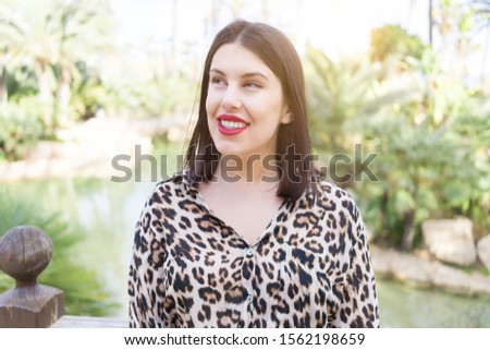 Young beautiful woman with red lips smiling happy at garden