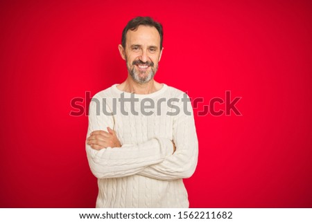 Handsome middle age senior man with grey hair over isolated red background happy face smiling with crossed arms looking at the camera. Positive person.