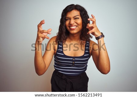 Transsexual transgender woman wearing striped t-shirt over isolated white background Shouting frustrated with rage, hands trying to strangle, yelling mad