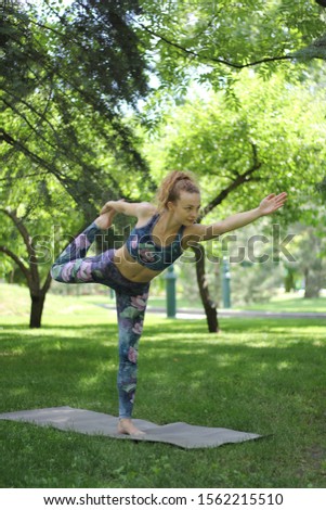 beautiful girl with blond hair practices yoga in the park